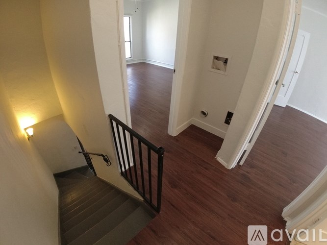 A staircase with a black railing and wooden steps leading to a white door.