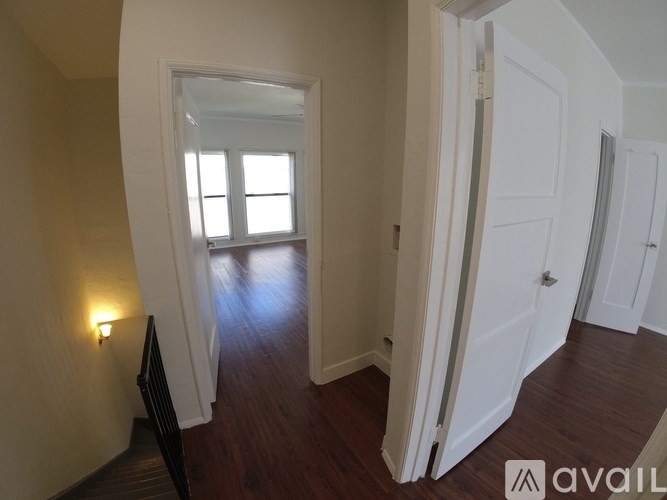 A hallway with a light on the wall and a door at the end.