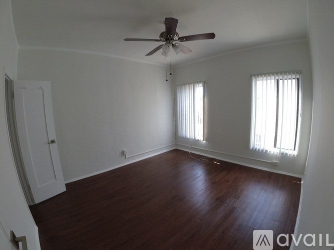 A room with a ceiling fan and wooden flooring.