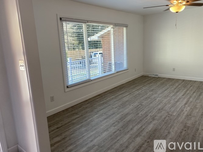 A room with a window covered by white blinds and a ceiling fan.