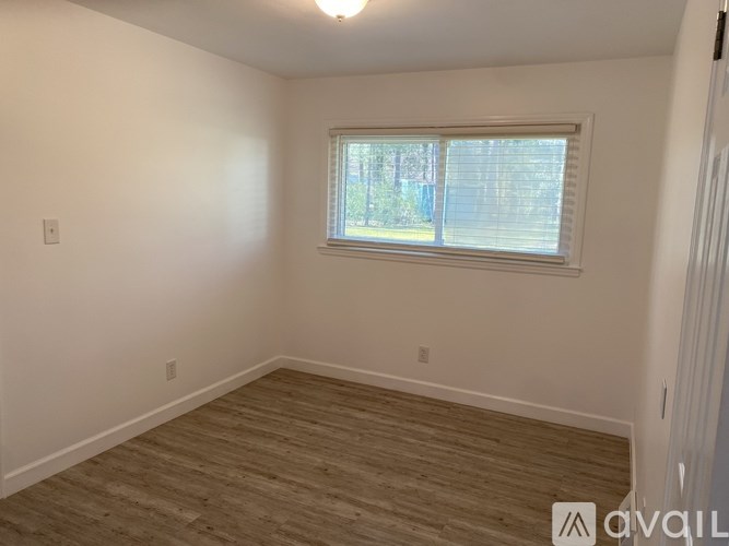 A room with a window and wooden flooring.