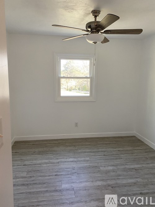 A room with a ceiling fan and a window.