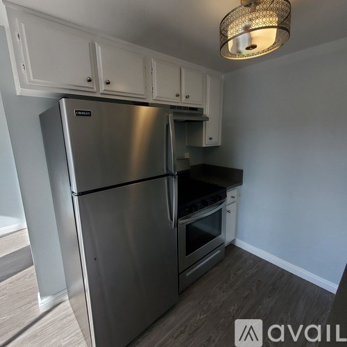 A kitchen with a stainless steel refrigerator and wooden flooring.