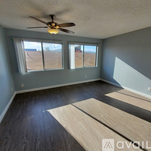 A room with a ceiling fan and wooden flooring.