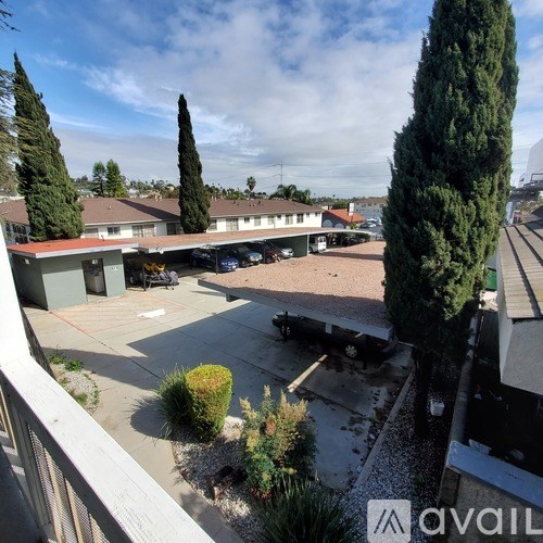 A view of a courtyard with a car and a tree.