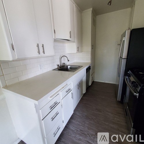A kitchen with white cabinets and a black fridge.