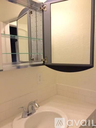 A bathroom with a white sink and a mirror with a silver frame.