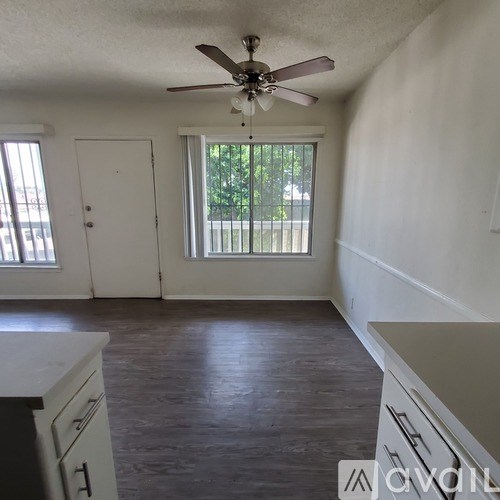 A room with a ceiling fan and sliding glass doors.