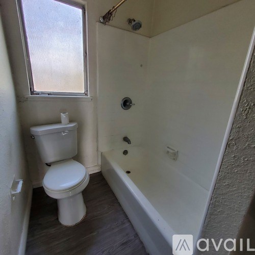 A small bathroom with a toilet, tub, and window.