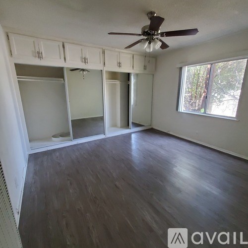 A room with a ceiling fan and wooden flooring.