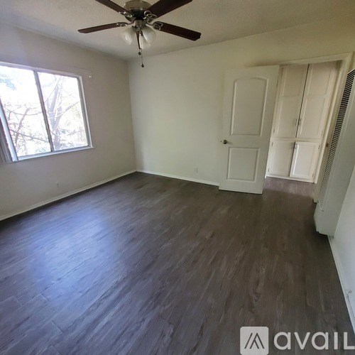 A room with a ceiling fan and wooden flooring.