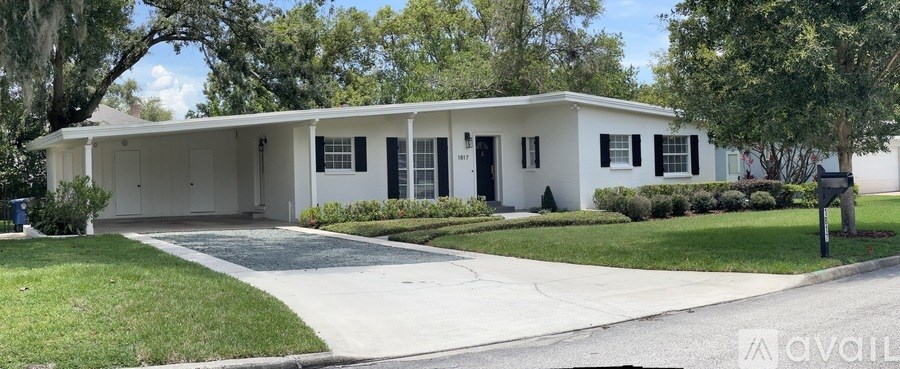 A white house with a black roof and a driveway in front.