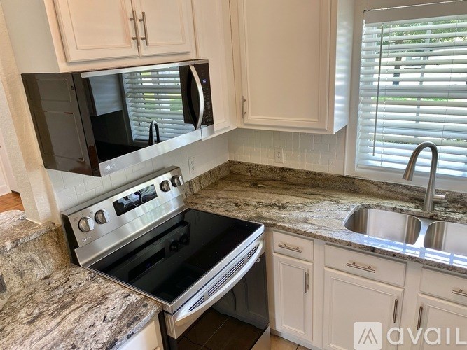 A kitchen with a granite countertop and a stainless steel sink.