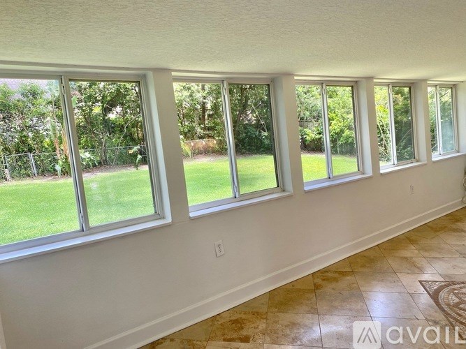 A room with a long row of windows overlooking a green lawn.