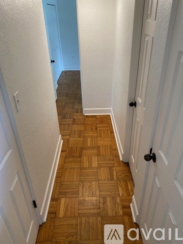 A hallway with a wooden floor and white walls.