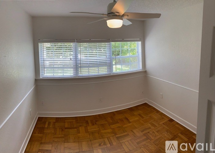A room with a ceiling fan and wooden flooring.
