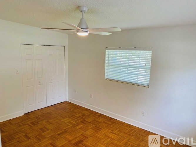 A room with a ceiling fan and a window with blinds.