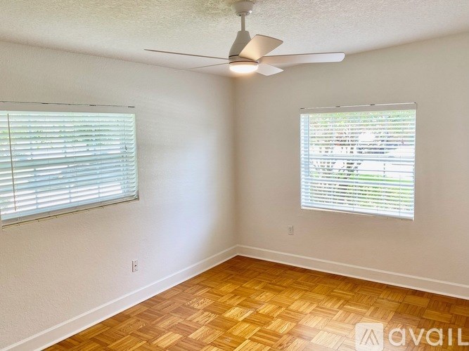 A room with a ceiling fan and two windows with blinds.