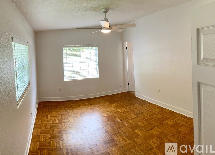 A room with wooden flooring and a window with blinds.