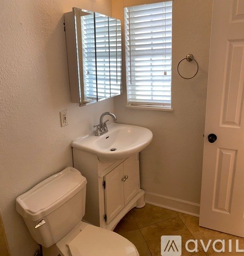 A bathroom with a toilet, sink, and mirror.