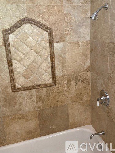 A bathroom with a tiled wall and a mirror.