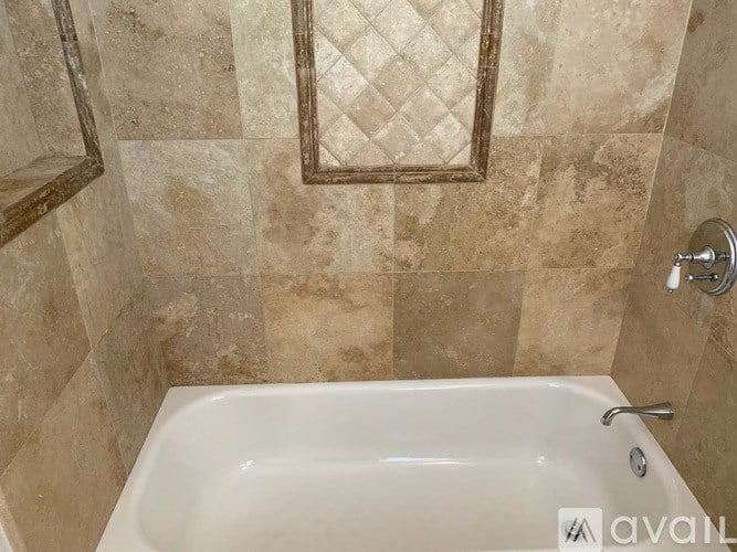A bathroom with a tiled wall and a bathtub.
