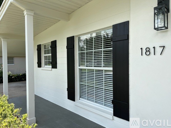 A white house with black shutters and a lantern on the wall.