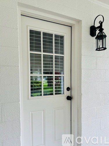 A white door with a black handle and a lantern on the wall.