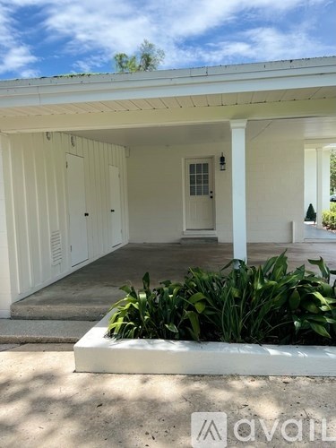 A white house with a porch and a plant in front.