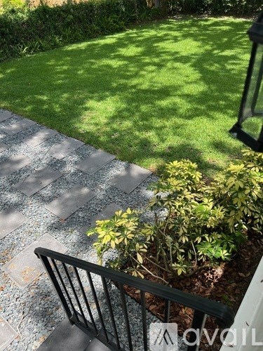 A black railing with a plant in front of it.