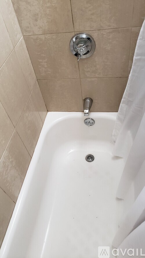 A white bathtub with a shower head above it.