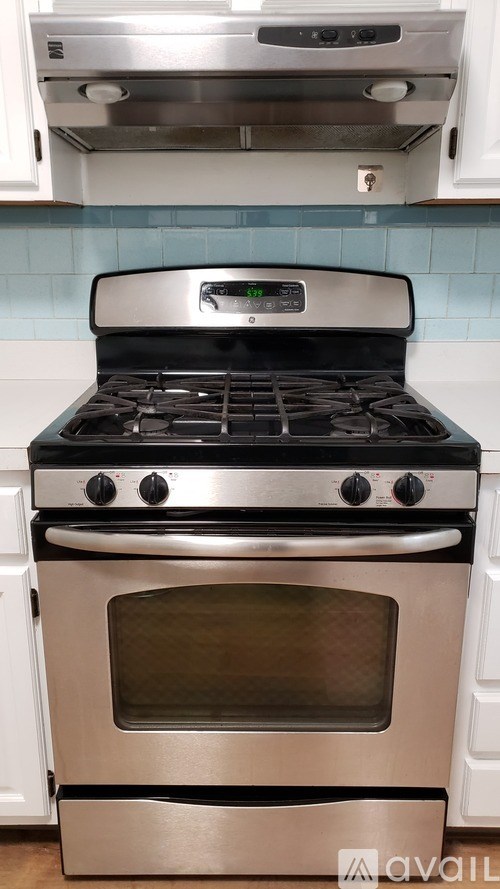 A stainless steel oven with a digital display is installed in a kitchen.