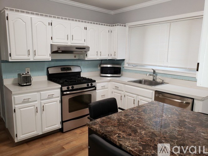 A kitchen with white cabinets and a granite countertop.