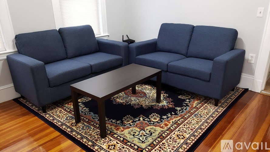 A dark blue sofa set with a wooden coffee table in front of a patterned rug.