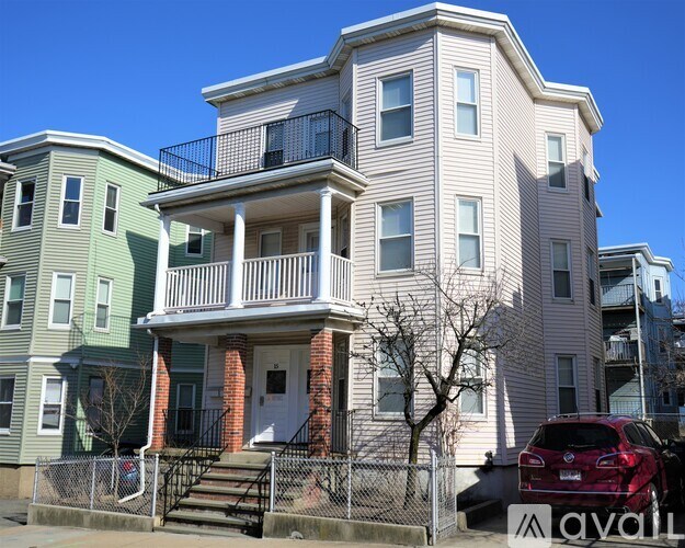 A row of houses with a car parked in front of the third one.