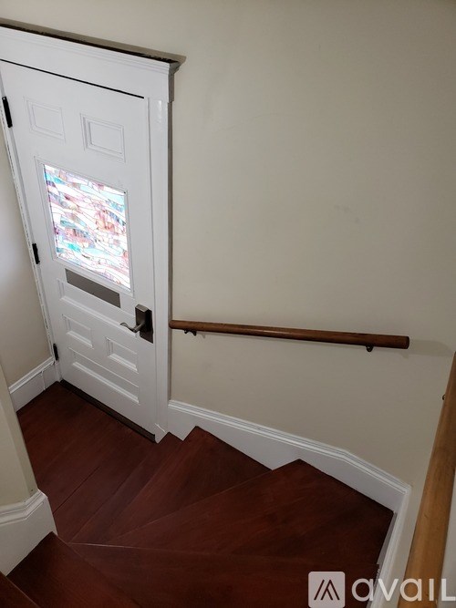 A white door with a glass window is in a room with a wooden staircase.