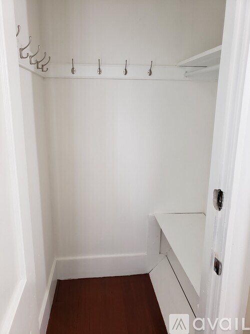 A small closet with a white door and a white shelf.