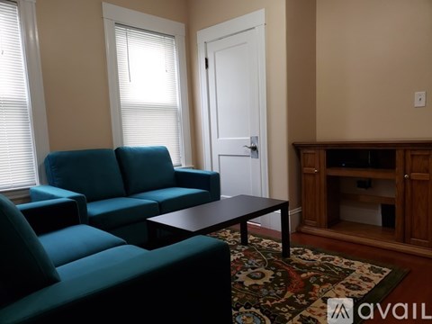 A living room with a blue couch and a wooden cabinet.