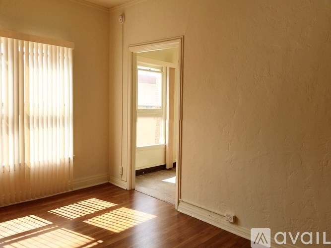 A room with a wooden floor and a door leading to another room.