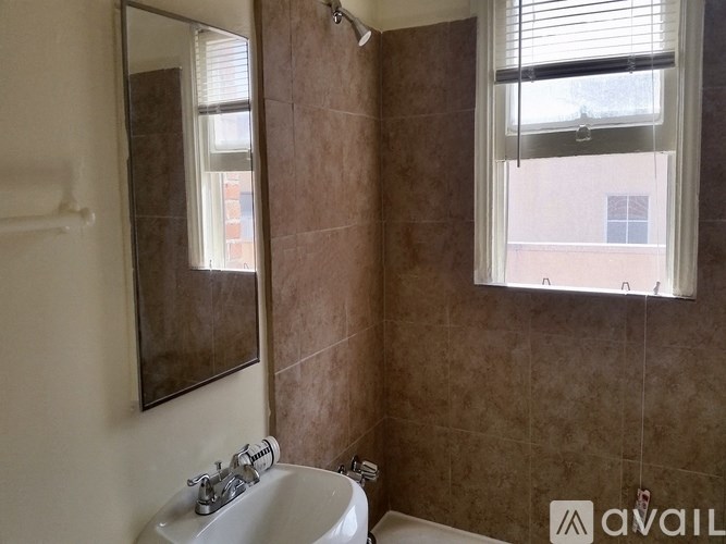 A bathroom with brown tiles and a white sink.