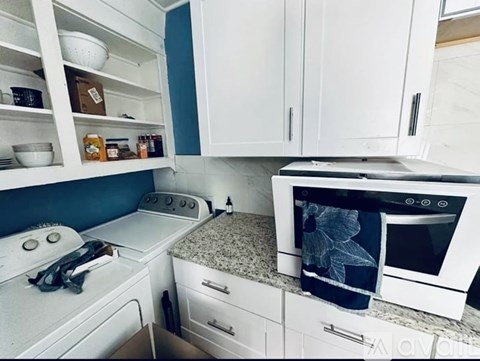 A kitchen with white appliances and cabinets.