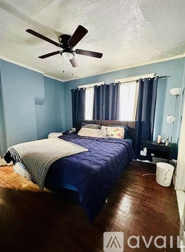 A bedroom with a bed, a ceiling fan, and a nightstand.