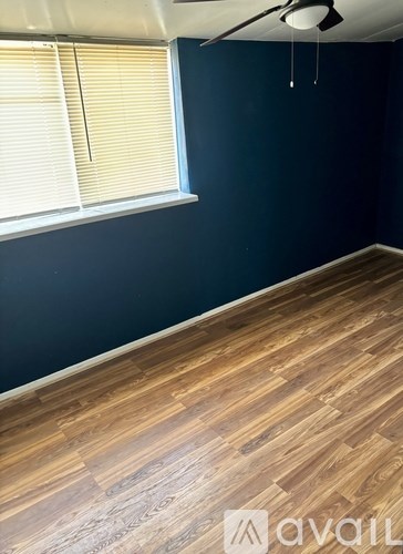 A room with wooden flooring and a window with blinds.