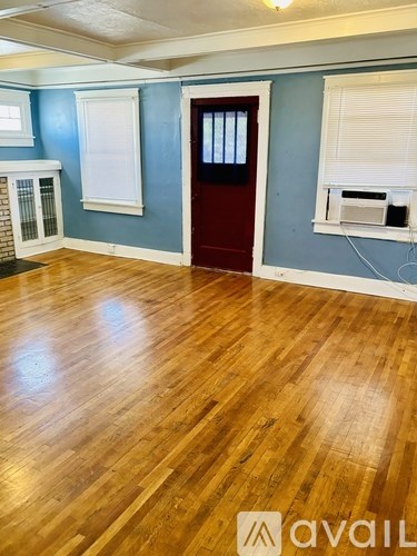 A room with wooden flooring and a red door.