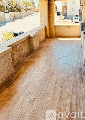 A wooden deck with a wall and a road in the background.