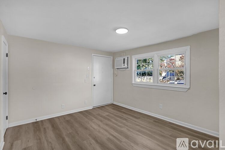 A room with a window showing a view of a garden and a white door.