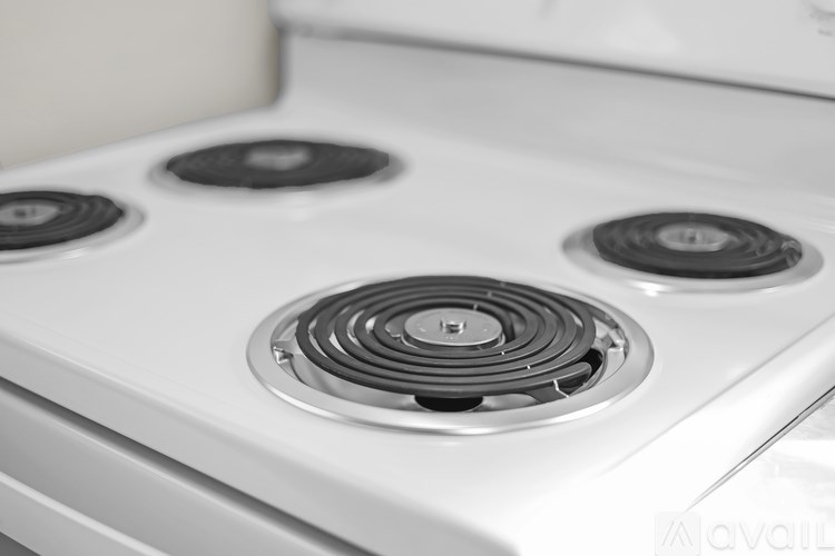 A white stove top with four burners, one of which is lit.