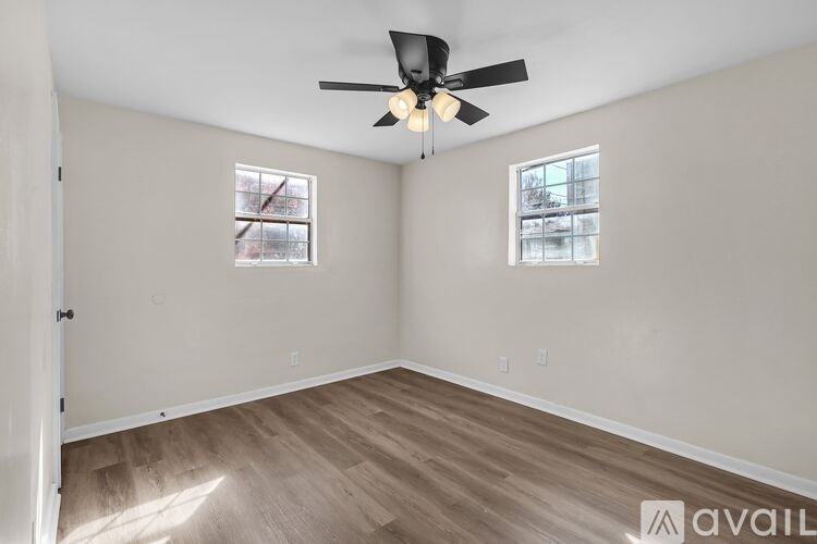 A room with a ceiling fan and two windows.