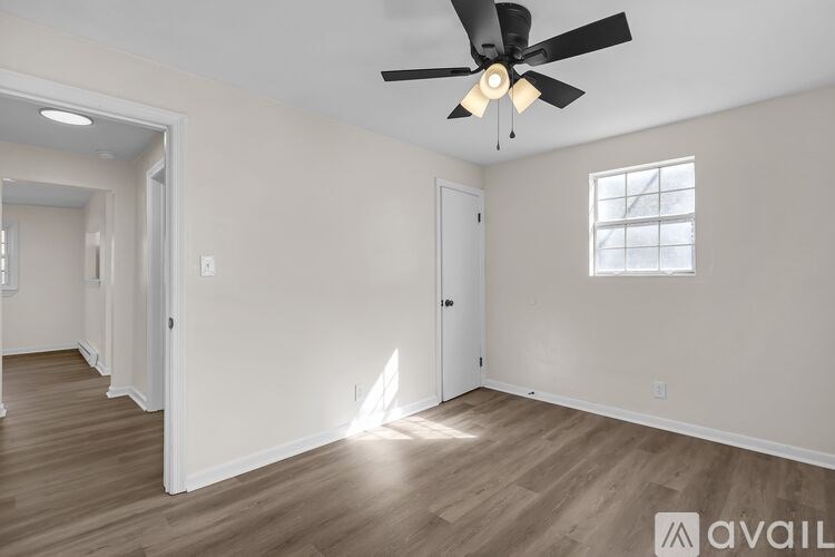A room with a ceiling fan and wooden flooring.