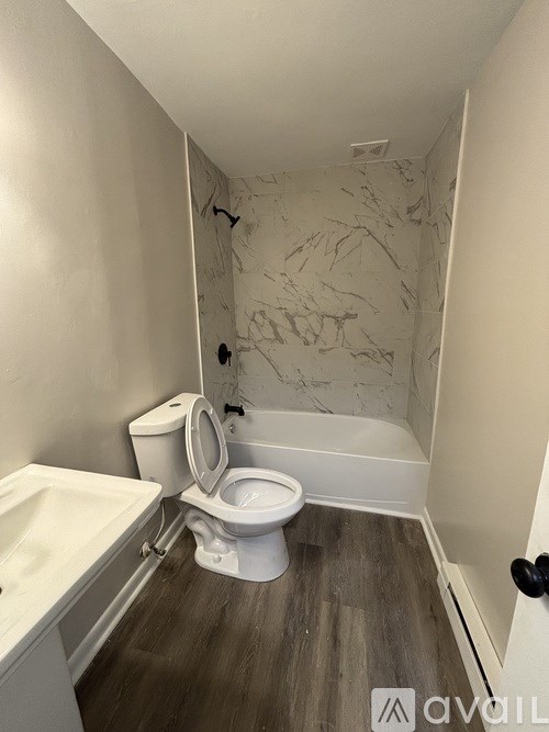 A bathroom with a toilet, sink, and marble wallpaper.